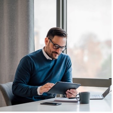 two business partners look at a tablet while standing on a balcony